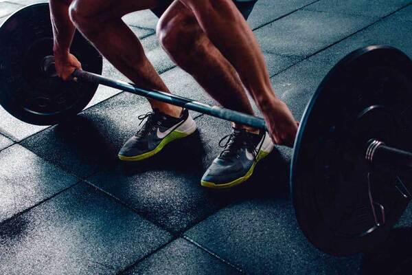 Adult outdoors with arms raised in a light stretch beneath open sky